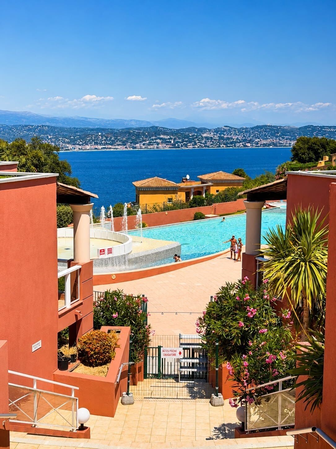 Un complexe hôtelier doté d'une piscine, offrant une vue sur la mer, et dont l'entrée est signalée par une pancarte indiquant : « Accès Psone obligatoire ».