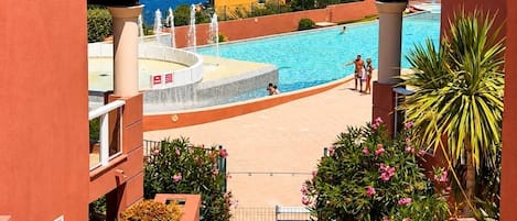A resort with a swimming pool, a view of the sea, and a gate labeled 'Accès Psone Obligatoire'.