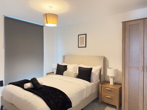 A neatly arranged bedroom with a bed, bedside tables, a wardrobe, and a hanging light fixture. - 2 Bed Flat - Sleeps 4 - Parking - Wifi (Manchester)