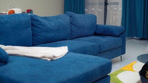 Un canapé bleu dans un salon moderne, avec une porte en verre et des rideaux bleus.