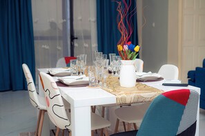 A dining table set with clear glasses, a white vase with flowers, and a remote control.