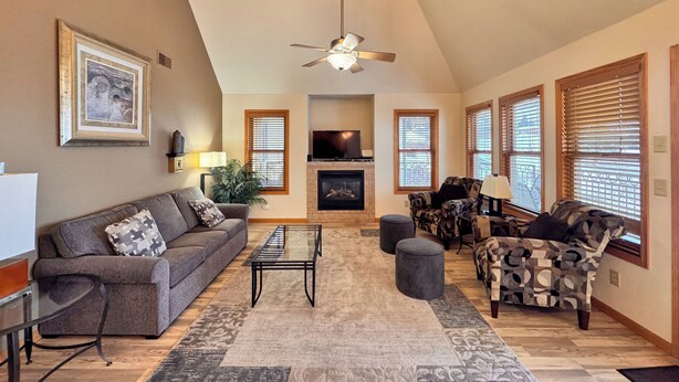 A living room with a sofa, armchair, ottoman, fireplace, television, and a ceiling fan. - 3BR Condo |  Bayfield Lake Views (Bayfield)
