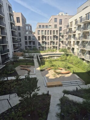 A modern apartment complex with multiple balconies, a central courtyard with greenery, and a mix of residential and commercial buildings in the background. - Smichov Luxury apartments (Prague 5)