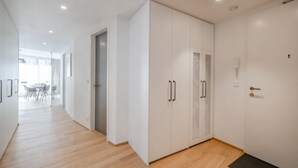 Un couloir moderne avec des armoires blanches, un plancher en bois et une porte donnant sur une pièce.