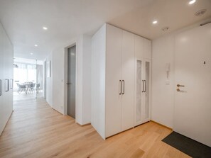 Ein moderner Flur mit weißen Schränken, Holzboden und einer Tür zu einem Zimmer.