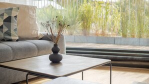 Un salon moderne avec un canapé gris, une table basse et un vase contenant des plantes séchées.