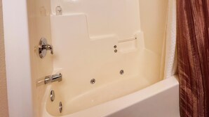 Eine weiße Badewanne mit Wasserhahn, Haltegriff und Ablass.