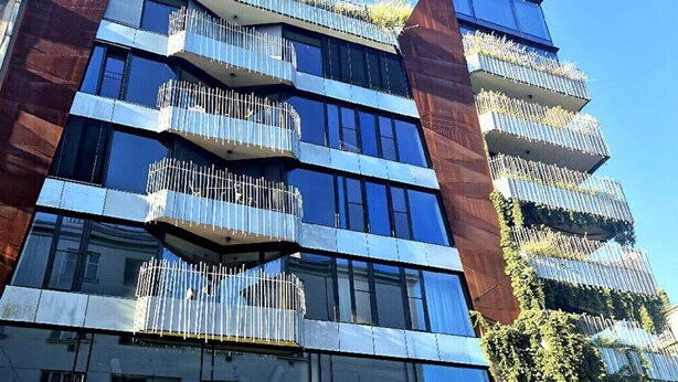 Un edificio moderno con varios balcones, ventanas grandes y un letrero que dice "The Hotel" con un logotipo.