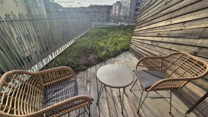 Terraza en la azotea con mobiliario de mimbre y vistas a la ciudad.