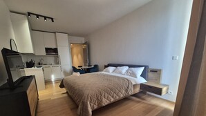 Un dormitorio moderno con una cama grande, un escritorio y una kitchenette.