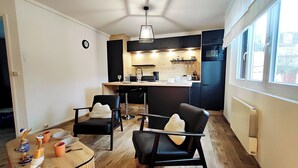 Une cuisine moderne avec un îlot central, des chaises noires et une table basse en bois.