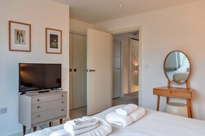 Ett hotellrum med en säng, en tv, en byrå, en spegel och två inramade tavlor på väggen.