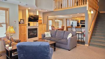 A spacious living room with a fireplace, a sofa, a coffee table, and a staircase leading to an upper level.