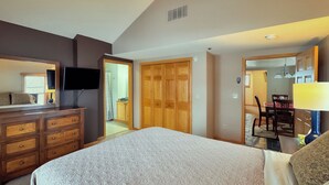 A bedroom with a bed, dresser, TV, and wooden closet. - Top-Floor Condo | Lake Views | Walk Downtown (Bayfield)