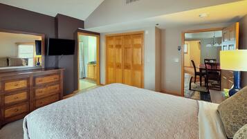 A bedroom with a bed, dresser, TV, and wooden closet.
