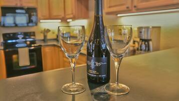A kitchen with wooden cabinets, a microwave, a stove, and a wine bottle with two glasses.
