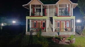 A two-story building with a balcony on the upper floor, a staircase leading to the entrance, and a small porch area with a table and chairs. - Hotel Dynasty Inn (Mal)