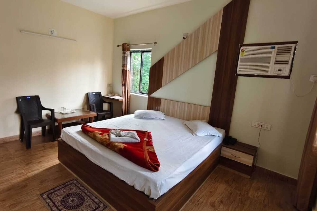 A hotel room with a large bed, a desk, a chair, and a window with curtains.