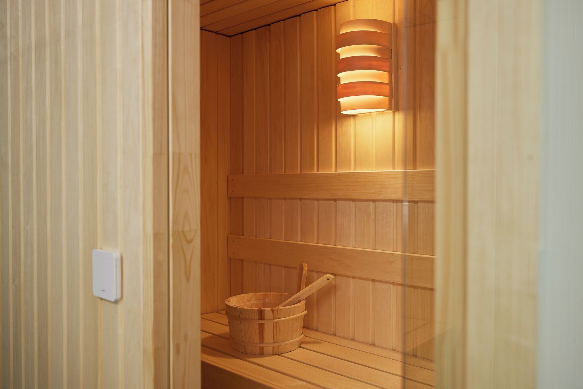 Una sauna de fusta amb un cub de fusta i una làmpada.