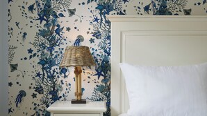 Una cama con ropa de cama blanca y una mesita de noche blanca con una lámpara.