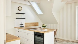 A modern kitchen with a skylight, white cabinetry, a built-in oven, and a wooden countertop.