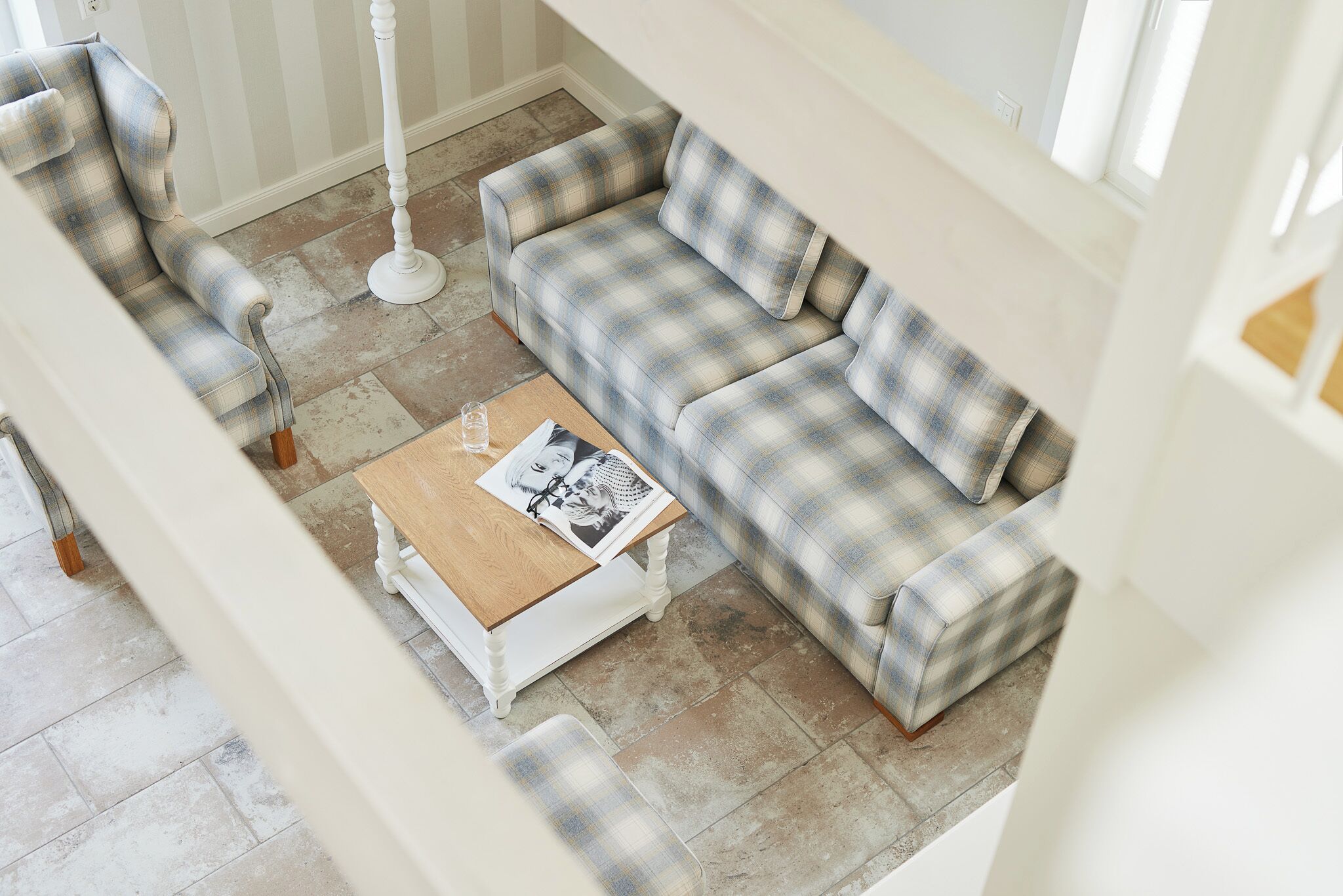 A living room with a plaid sofa, a wooden coffee table, and a white floor lamp.
