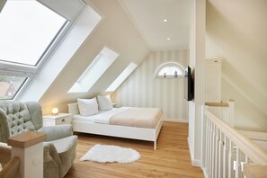 Un dormitorio con tragaluz, cama, silla y suelo de madera.