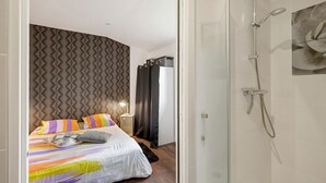 Ein modernes Hotelzimmer mit Bett, Dusche und Wand mit geometrischem Muster.