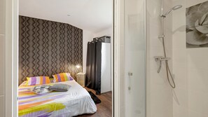 A modern hotel room with a bed, a shower, and a wall with a geometric pattern.