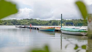 Un lac paisible où des bateaux sont amarrés à un quai, le tout entouré d’une végétation luxuriante.