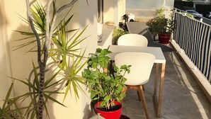 En balkon med plantekrukker, et hvidt lanterne og et bord med stole.