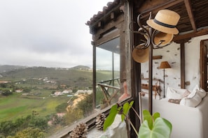 A room with a view of a rural landscape, a wooden ceiling, and a window with a view.
