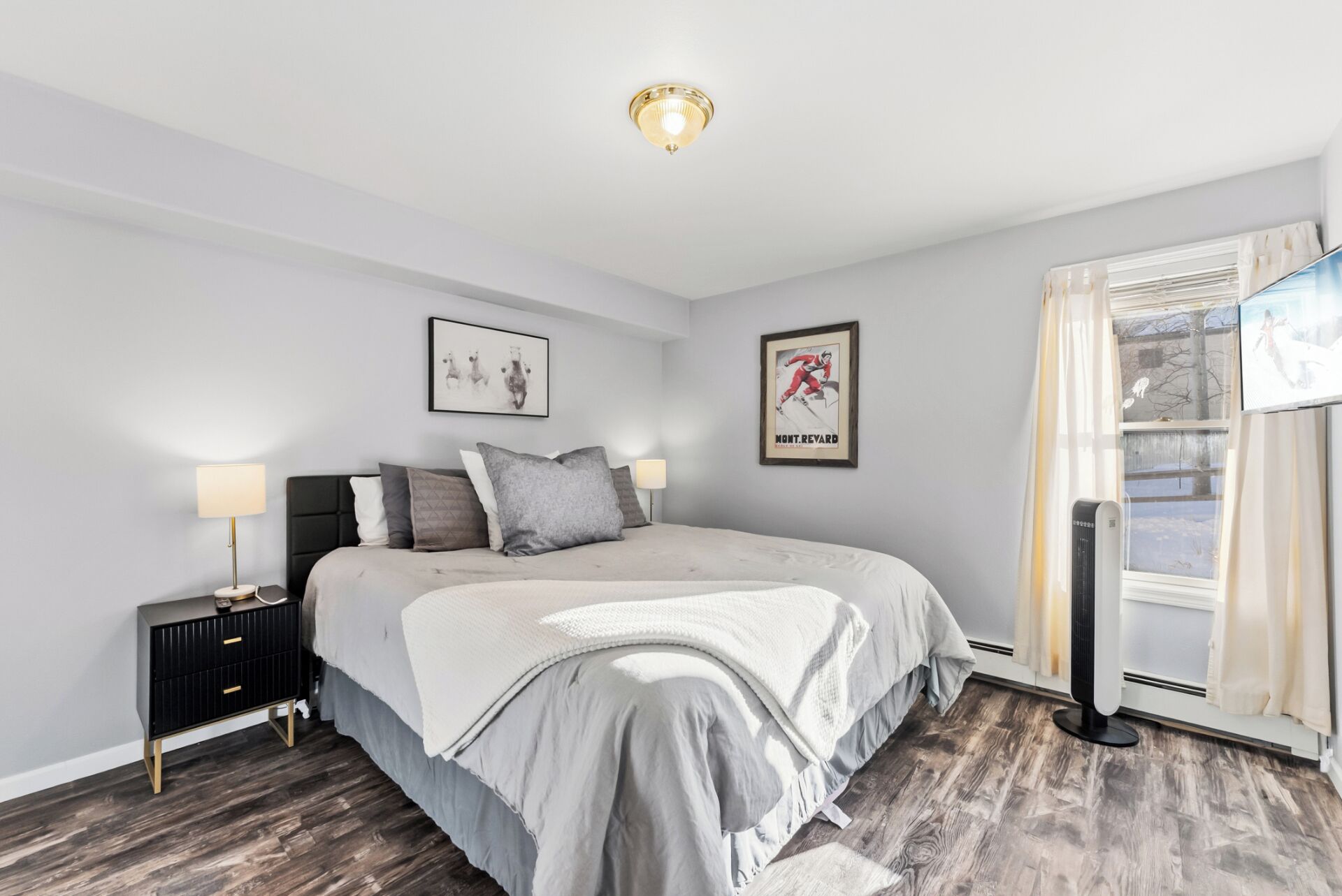A bedroom with a bed, bedside tables, a window with curtains, and a ceiling light.