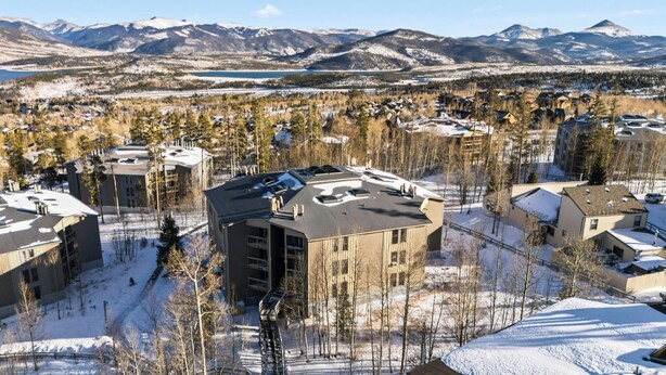 A residential area with modern buildings, a ski resort in the background, and a clear view of the mountains. - Treehouse C106 - Renovated Condo, Pool, Hot Tub, Game Room + Central Summit County Location (Silverthorne)