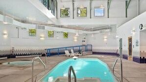 An indoor swimming pool with clear water, surrounded by lounge chairs and a blue safety railing. - Treehouse C106 - Renovated Condo, Pool, Hot Tub, Game Room + Central Summit County Location (Silverthorne)