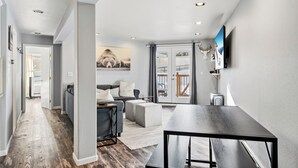 A modern living room with a grey sofa, a wooden coffee table, and a television mounted on the wall. - Treehouse C106 - Renovated Condo, Pool, Hot Tub, Game Room + Central Summit County Location (Silverthorne)