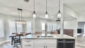 A spacious kitchen with a large island, white cabinetry, and a stainless steel dishwasher. - Twilight Mist - 3/2 in The Village of Poinciana (Poinciana, The Villages)