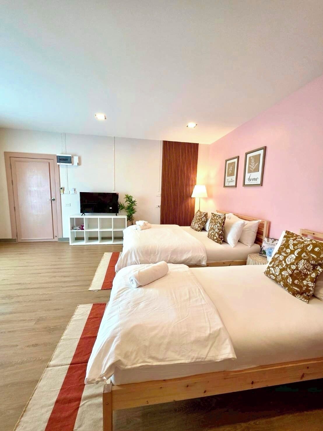Habitación de hotel con dos camas, televisor, escritorio y ventana con cortinas.