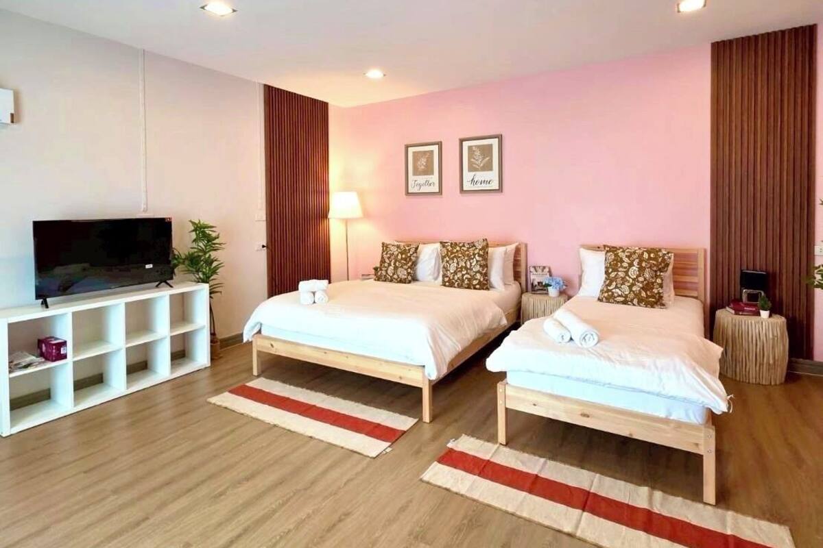 Un dormitorio moderno con dos camas, un televisor y una mesita de noche con lámpara.