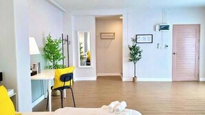 Une chambre d’hôtel avec un lit, un bureau, une chaise et une petite table. La chambre est dotée d’une porte et d’une fenêtre.