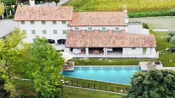 A large, two-story building with a swimming pool, surrounded by well-maintained lawns and trees.