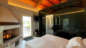A modern bedroom with a fireplace, a large bed, and a glass shower enclosure.