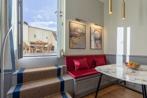 A modern interior with a red sofa, a marble table, and a view through a window. - Design Florence Suite with large terrace (Firenze)