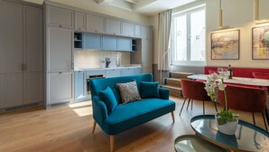 A modern kitchen with grey cabinets, a teal sofa, and a dining area with red chairs. - Design Florence Suite with large terrace (Firenze)