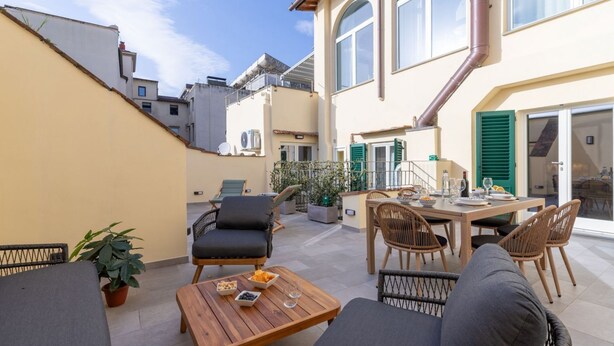 A spacious outdoor patio with a dining area, seating, and potted plants. - Design Florence Suite with large terrace (Firenze)