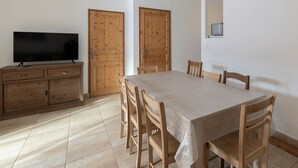 Zona de menjador amb taula i cadires, armaris de fusta i televisió.