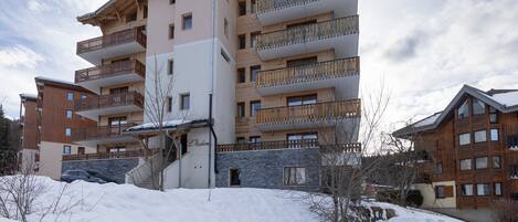 A multi-story hotel with balconies, a stone facade, and a snowy landscape.