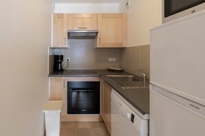 A compact kitchen with a Bosch dishwasher, a built-in oven, a coffee maker, and a sink. - Modern Apartment at the Foot of the Slopes in Morillon 1100 (Morillon)