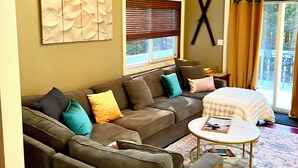 A living room with a sectional sofa, a coffee table, and a wooden ceiling.