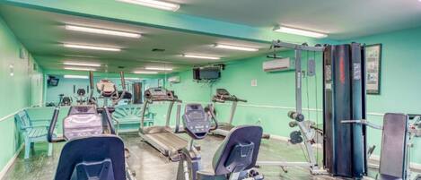 Un gimnasio con cintas de correr, elípticas y equipo de pesas.